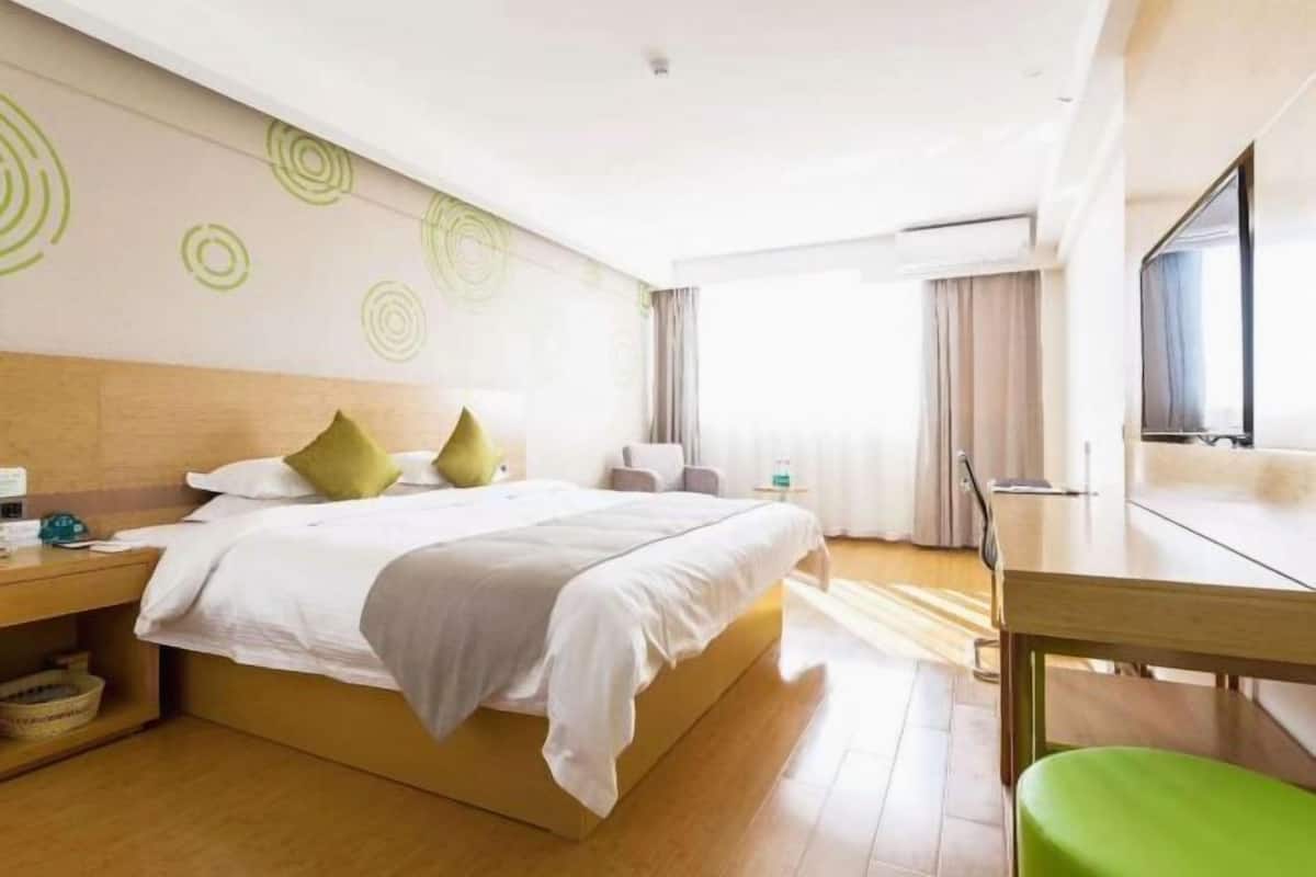 Una habitación de hotel moderna con una cama grande, un escritorio y una televisión.