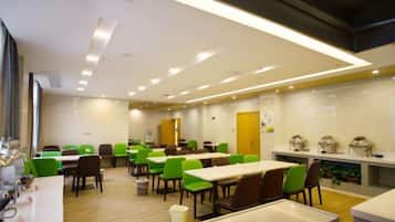 A modern dining area with multiple tables and chairs, a kitchen counter, and a door in the background.