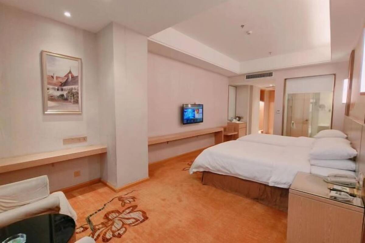 A hotel room with a bed, a TV, a desk, and a chair.