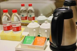 Preparación para el desayuno en una habitación de hotel, con té, café y aperitivos envasados.