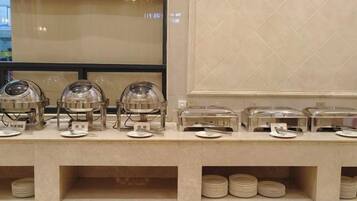 A buffet setup with multiple serving stations, each with a dome cover and a plate.