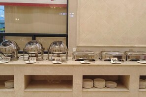 A buffet setup with multiple serving stations, each with a dome cover and a plate. - Vienna International Hotel (Wugang Shaoyang) (Wugang)