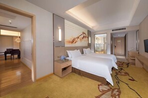 Habitación de hotel con una cama grande, un escritorio con silla, televisor de pantalla plana y un ventanal amplio.