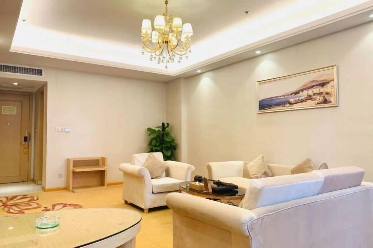 A living room with a chandelier, two sofas, a coffee table, and a painting on the wall.