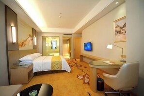A hotel room with a bed, a desk, a chair, a television, and a bathroom visible through a glass door. - Vienna International Hotel (Wugang Shaoyang) (Wugang)