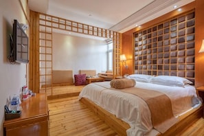 A bedroom with a bed, wooden floor, a TV, a desk, and a window. - Wanhe Haosheng Hotel (Lishui)