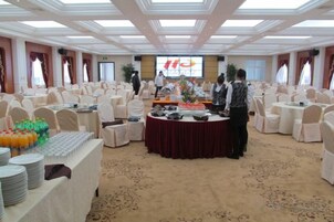 Un salón de banquetes con mesas redondas, sillas y una disposición tipo bufé.