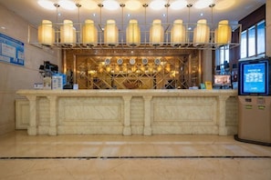 A reception area with a marble counter, pendant lighting, a digital kiosk, and a wall-mounted display. - Wanhe Haosheng Hotel (Lishui)