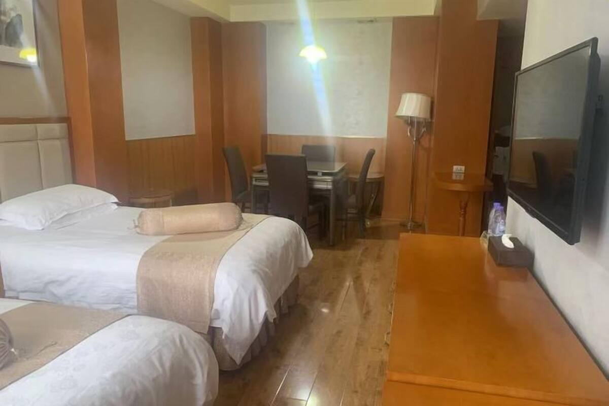 Hotellihuone, jossa on kaksi sänkyä, työpöytä, tuoli, televisio ja lamppu.