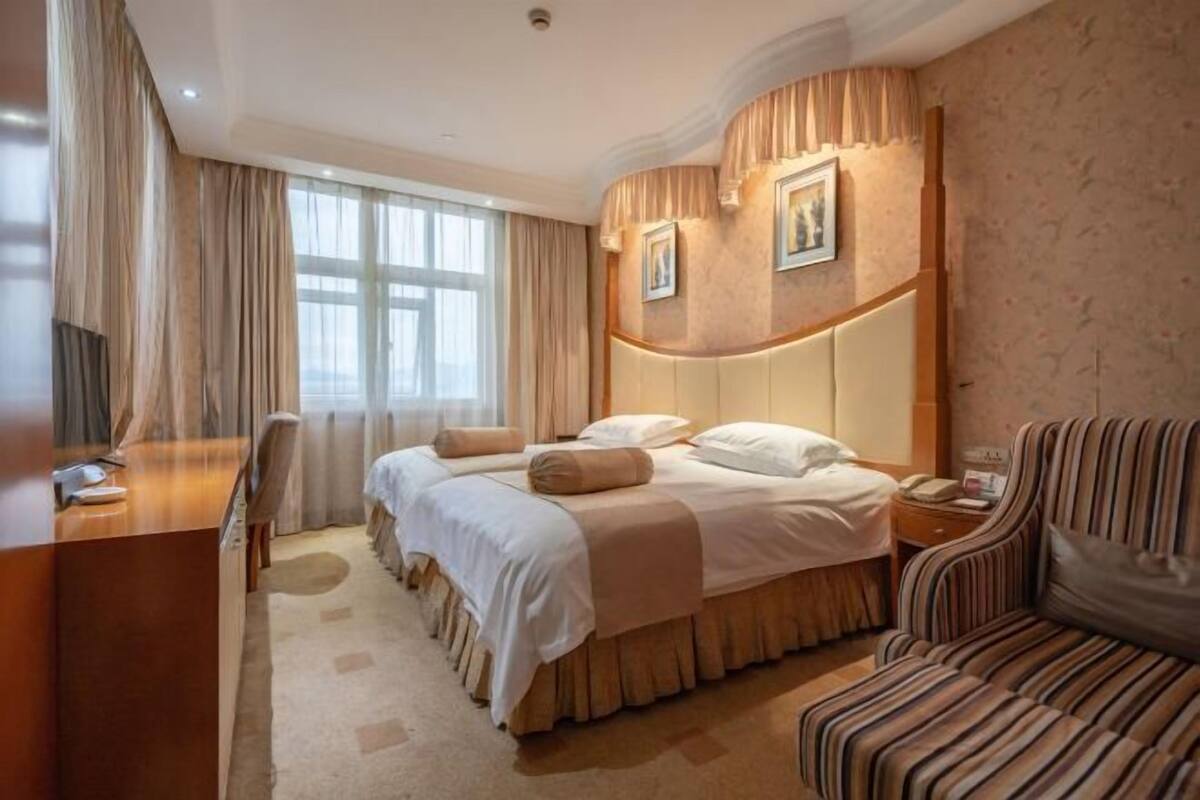 Hotellihuone, jossa on suuri sänky, työpöytä, tuoli ja sohva.