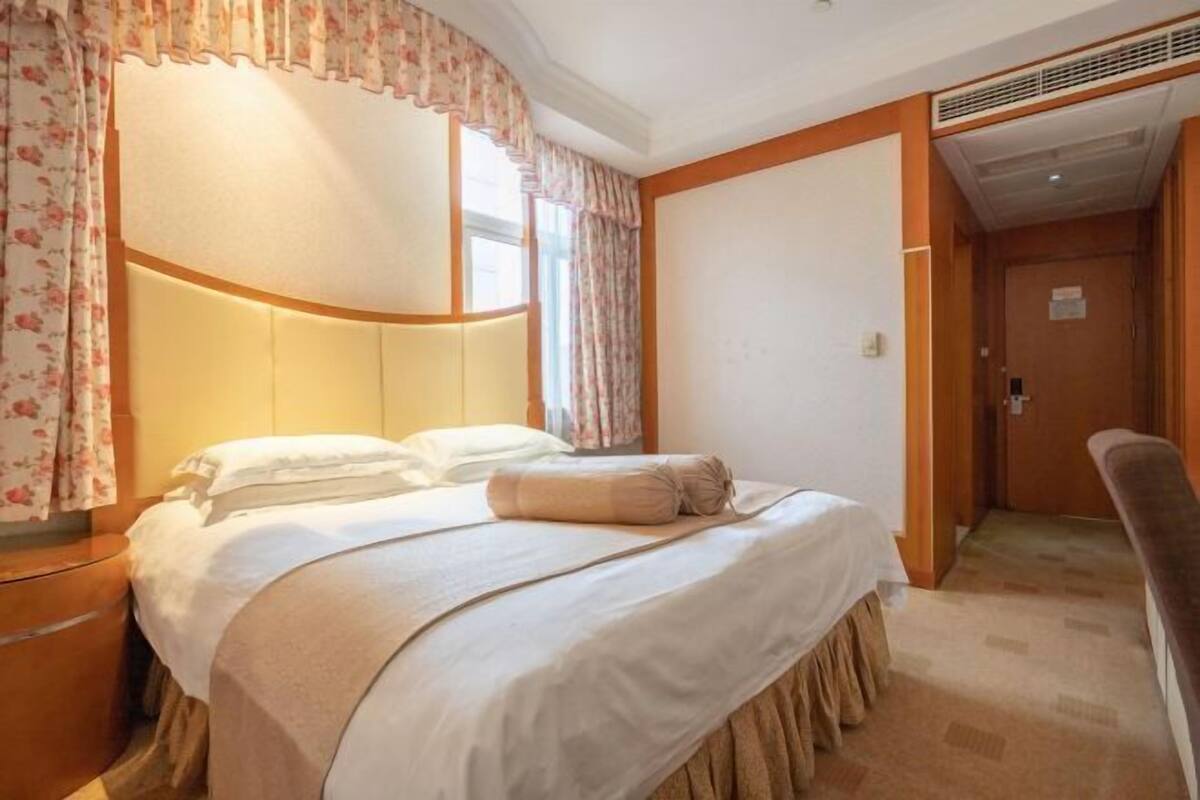 Hotellihuone, jossa on sänky, yöpöytä, tuoli ja ovi.