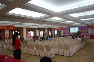 Un salón de conferencias con filas de sillas, un atril y una pantalla para presentaciones.