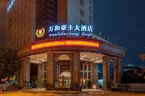 A hotel with a prominent sign, large columns, and a covered entrance area. - Wanhe Haosheng Hotel (Lishui)