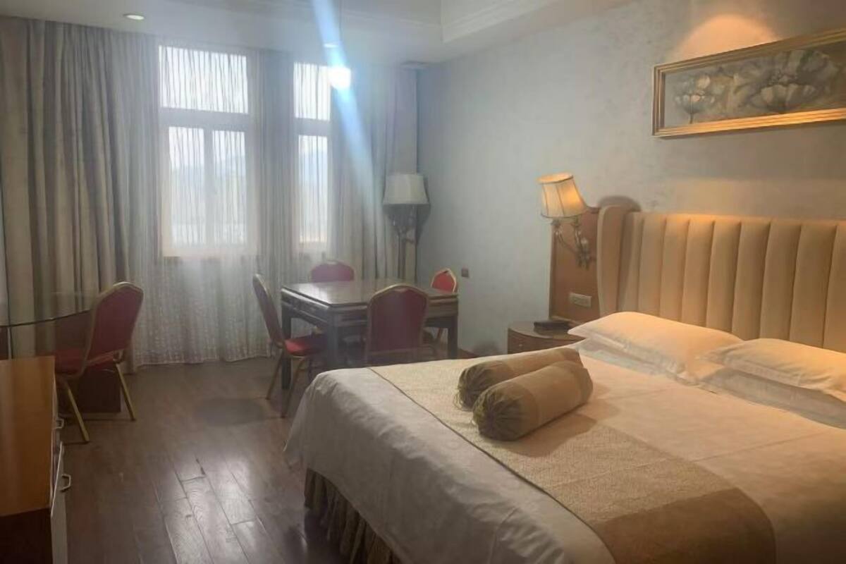 Hotellihuone, jossa on sänky, työpöytä, tuoli ja lamppu.