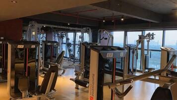 Een fitnessruimte met diverse trainingsapparaten, grote ramen en een hoge nok.