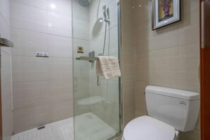 A bathroom with a glass-enclosed shower, a toilet, and a framed picture on the wall. - Wanhe Haosheng Hotel (Lishui)