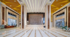 A spacious lobby with a marble floor, large windows, and a central decorative wall. - Vienna International Hotel (Shenzhen)