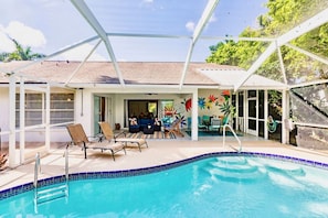 A pool area with lounge chairs, a dining area, and a covered patio.