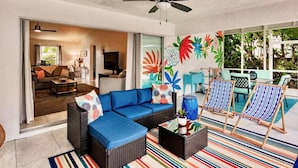 A modern living room with a blue sofa, wicker furniture, and colorful striped rugs.