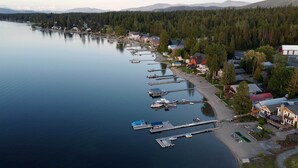 A lakeside town with docked boats, houses, and a forested backdrop. - Charming Lakefront Cabin w/ Deck & Fire Pit! (Newport)