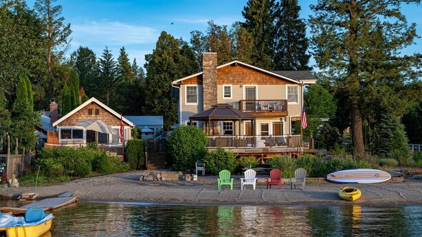 A waterfront property with a large house, a dock with boats, and a kayak. - Charming Lakefront Cabin w/ Deck & Fire Pit! (Newport)