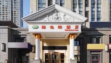 Een hotelgevel in klassieke stijl, met een centrale ingang en een bord met Chinese karakters.