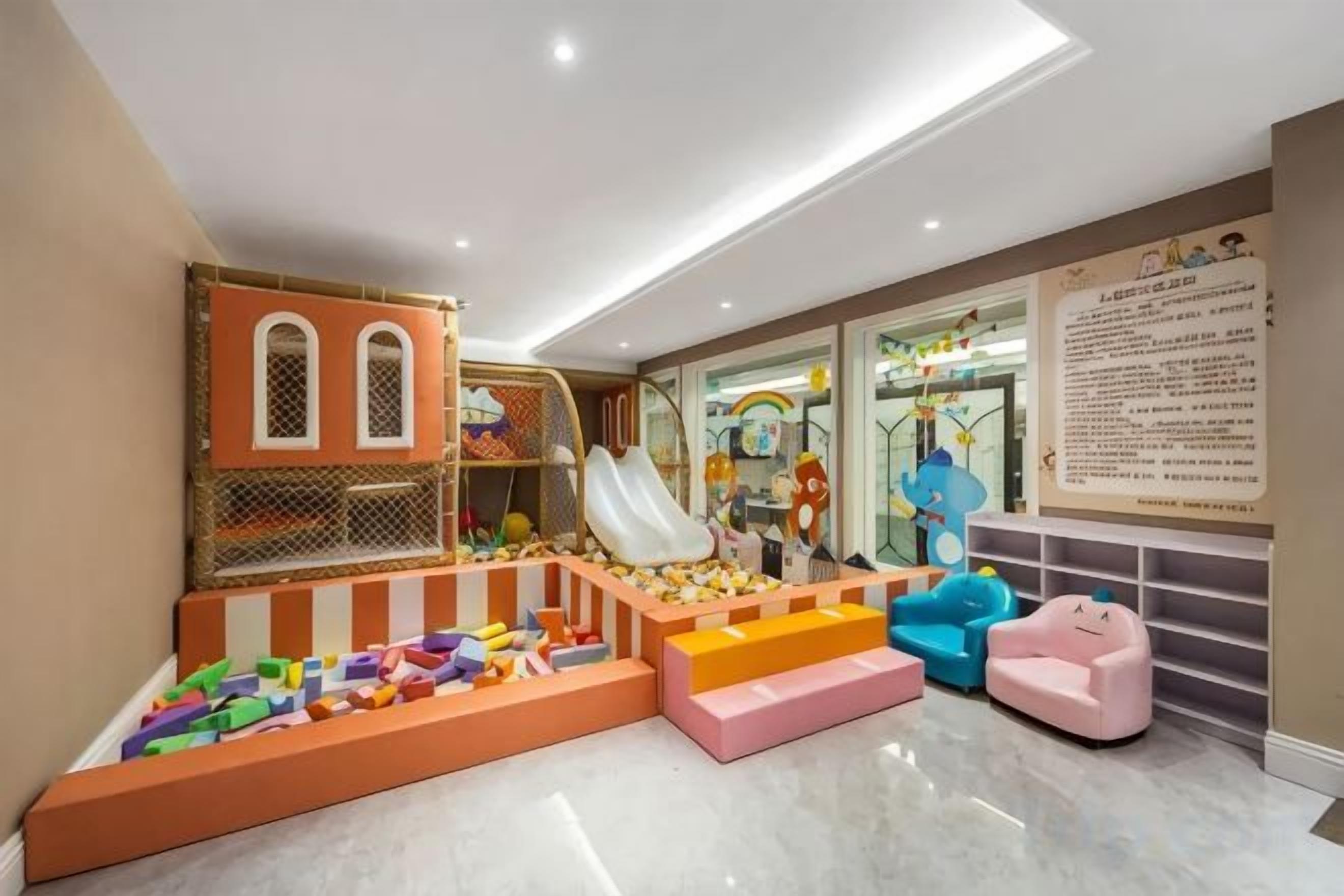 A children's play area with a slide, climbing net, and soft play structures.