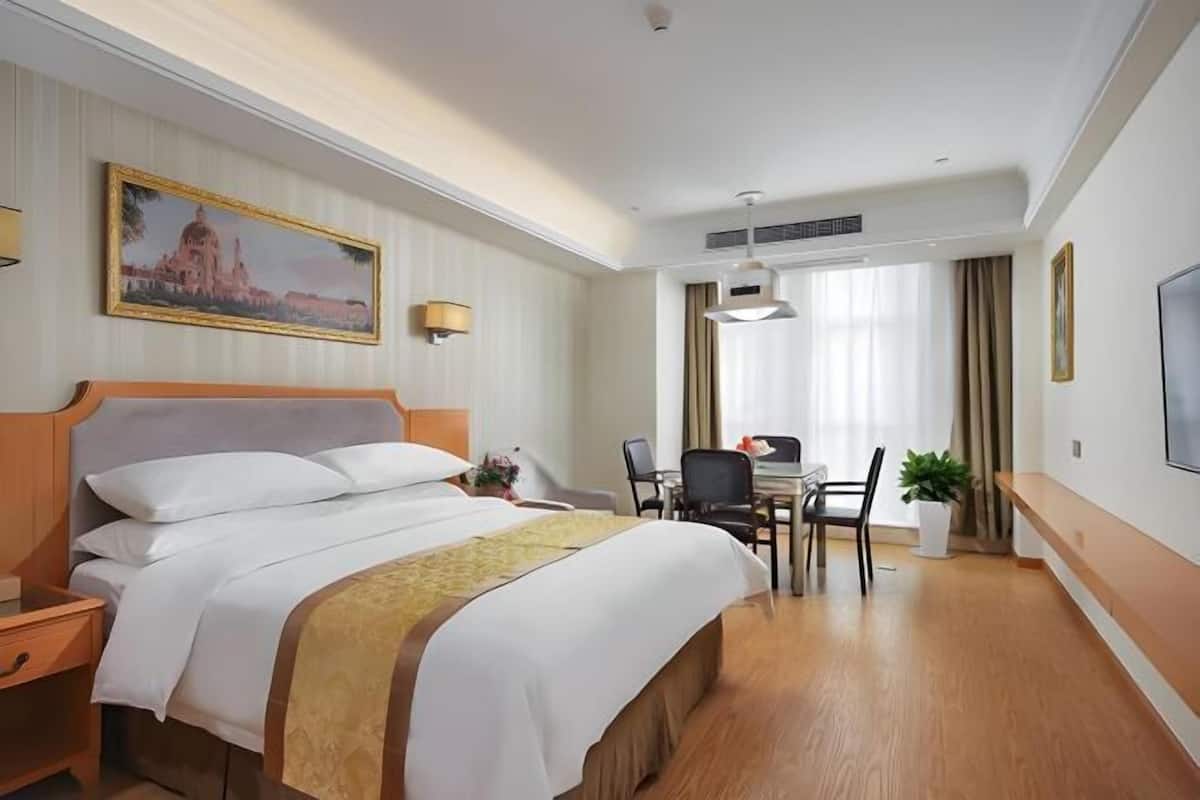 Une chambre d’hôtel avec un lit, un bureau, une chaise et un tableau au mur.