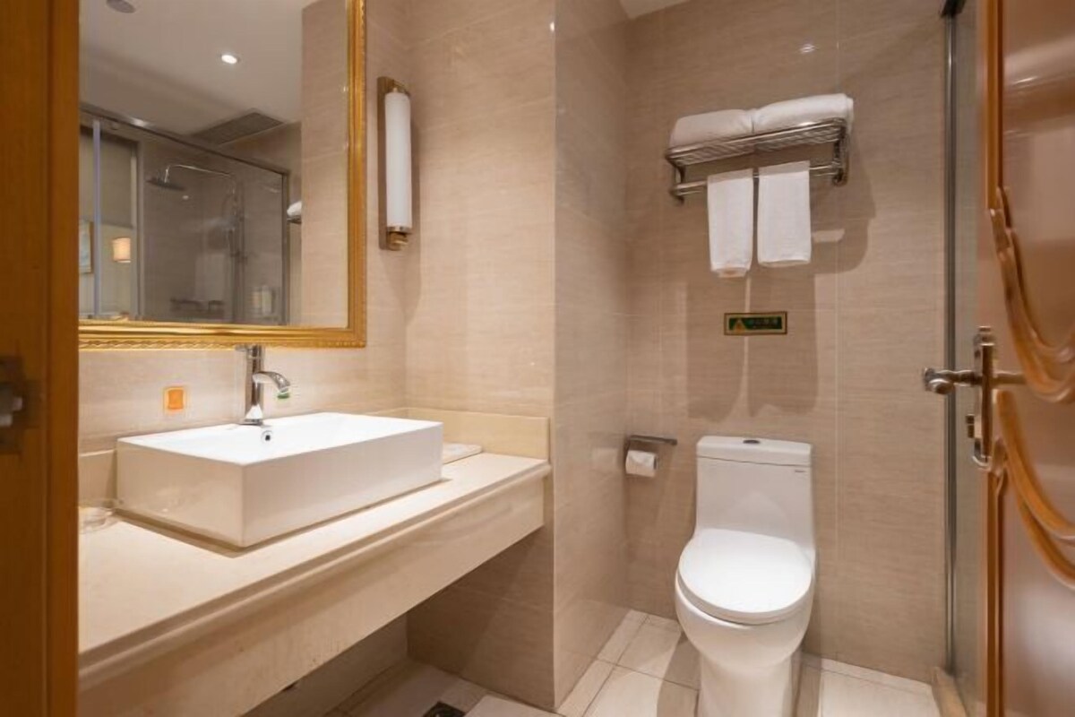 Ein modernes Badezimmer mit einem weißen Waschbecken, einer Toilette und einer Duschkabine aus Glas.