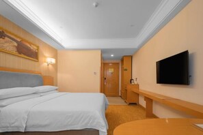 Ein Hotelzimmer mit Bett, Schreibtisch, Fernseher und einem Bild an der Wand.
