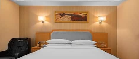 Una habitación de hotel con una cama, dos lámparas de noche, un sillón de masaje y un cuadro en la pared.