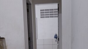 Een kamer met een bruine bank, een witte deur met een rasterpatroon en een betegelde vloer.