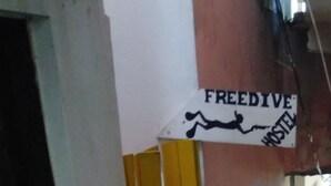 Een smalle steeg met een gele ladder tegen een muur, een bord waarop 