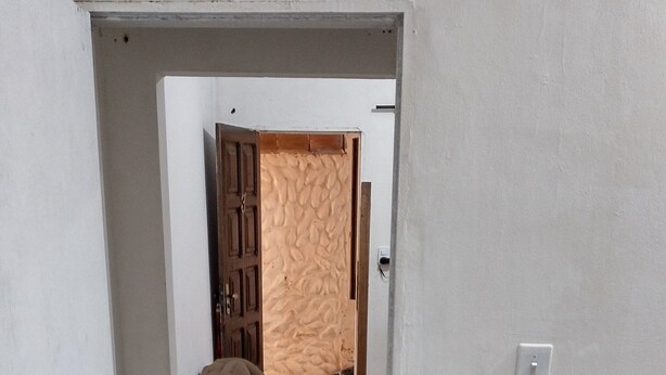 Een kamer met een houten vloer, een bed met witte beddengoed en een bank met een bruine hoes.