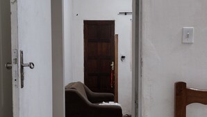 Een smalle gang met houten vloer, een donkerbruine bank en een houten bedframe.