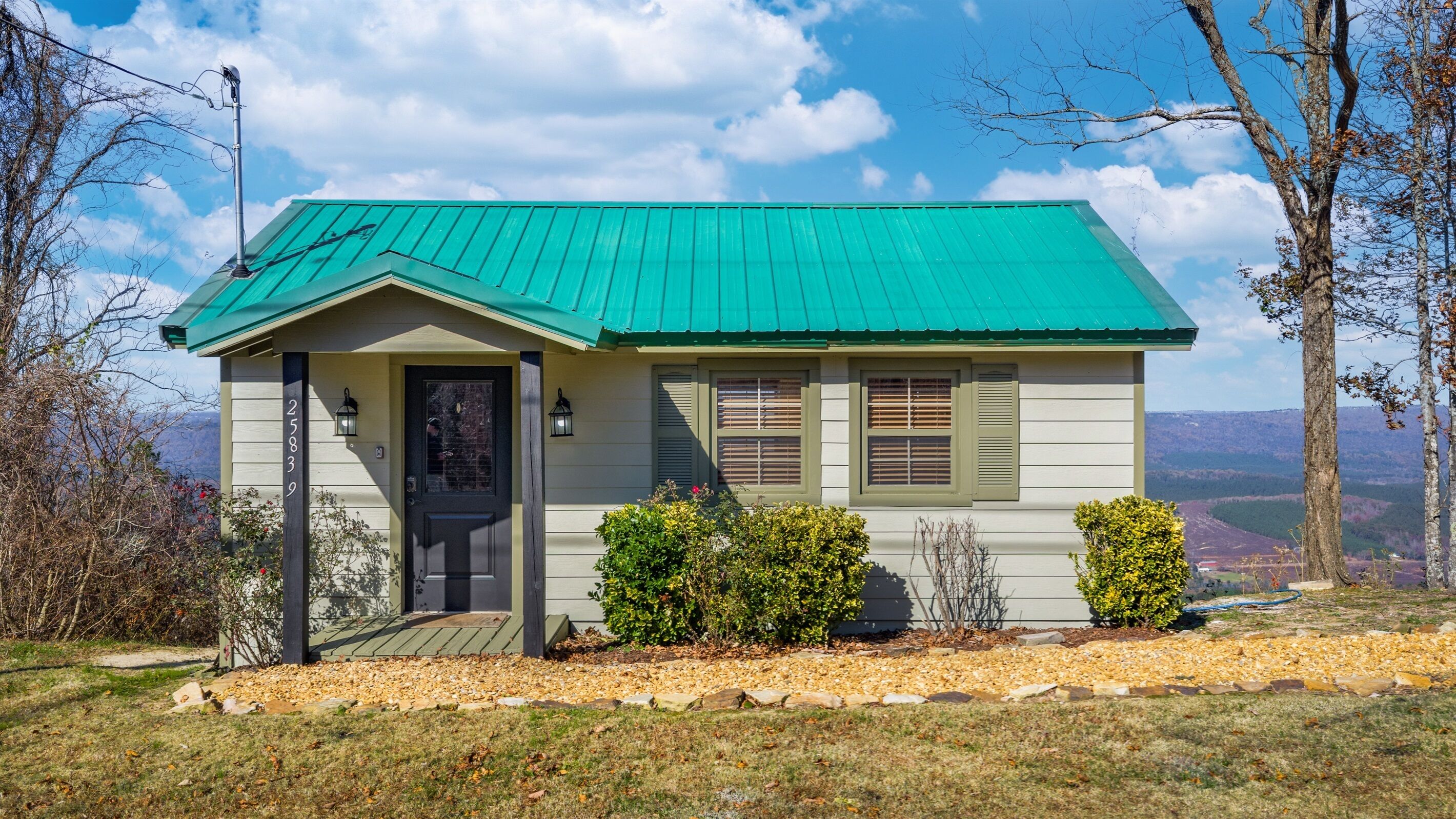 A small, single-story house with a green roof and a front porch.