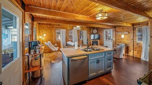 Ein Interieur einer Holzhütte mit Küche, Essbereich und Wohnraum.