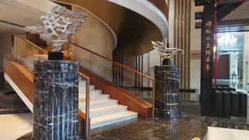Eine Lobby mit Marmorsäulen, einer Treppe und einem Empfangsbereich.
