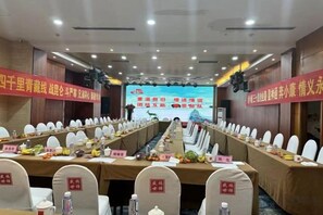 Une salle de conférence avec une longue table, des chaises et un écran à l’avant.