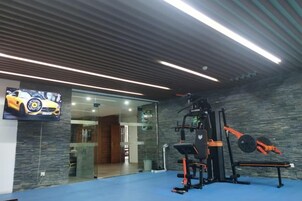 Un gimnasio con equipo de ejercicio, un televisor y suelo azul.
