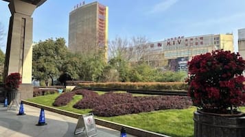 A landscaped area with a building in the background, a sign, and a few potted plants.