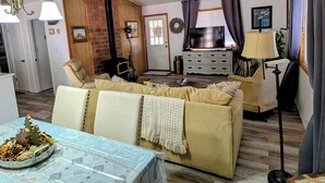 Un salon comprenant un canapé, une table à manger, un ventilateur de plafond et une cheminée.