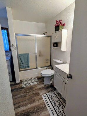 Un baño con ducha, inodoro y tocador.