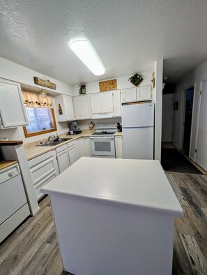 A kitchen with white cabinets, a central island, a refrigerator, and a stove.