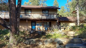 A two-story house with a balcony, surrounded by trees and a stone pathway. - 3 Room Cozy Suite in the Pines, near Downtown Prescott & many other attractions (Prescott)