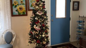 A living room with a decorated Christmas tree, a blue door, and a chair. - 3 Room Cozy Suite in the Pines, near Downtown Prescott & many other attractions (Prescott)