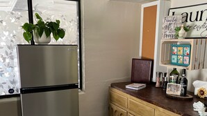 A kitchen with a stainless steel refrigerator, wooden cabinets, a countertop with various items, and a patterned rug. - 3 Room Cozy Suite in the Pines, near Downtown Prescott & many other attractions (Prescott)