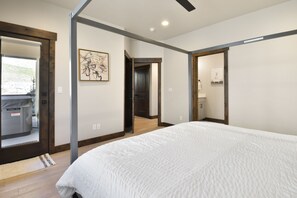 Un dormitorio moderno con una cama grande, un baño con lavamanos y espejo, y una puerta que da a otra habitación.