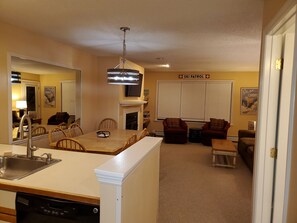 A living room with a fireplace, a dining area, and a kitchen with a dishwasher.
