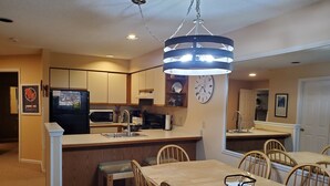 A modern kitchen with a central island, wooden chairs, and a dining table.